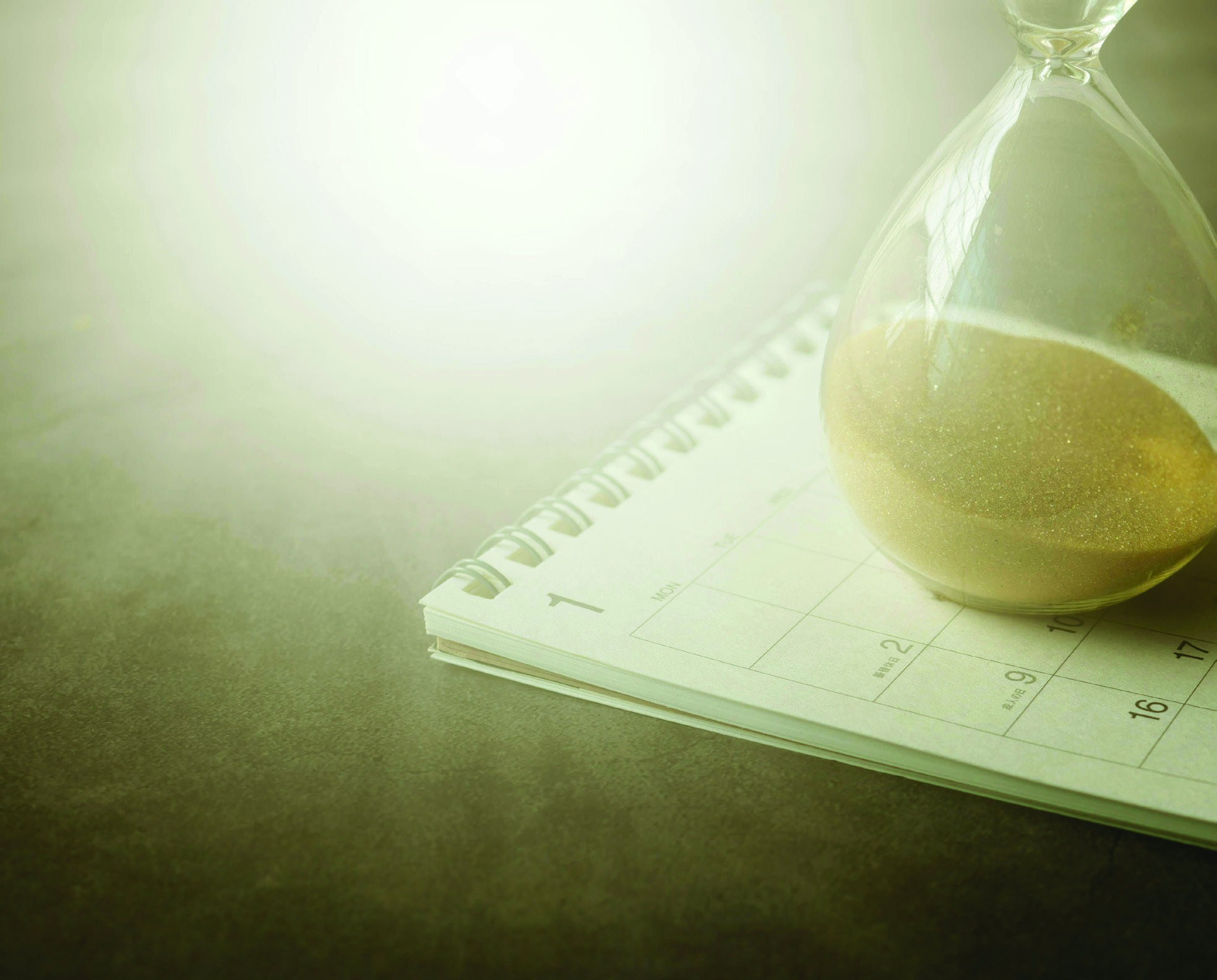 An hourglass beside a notebook